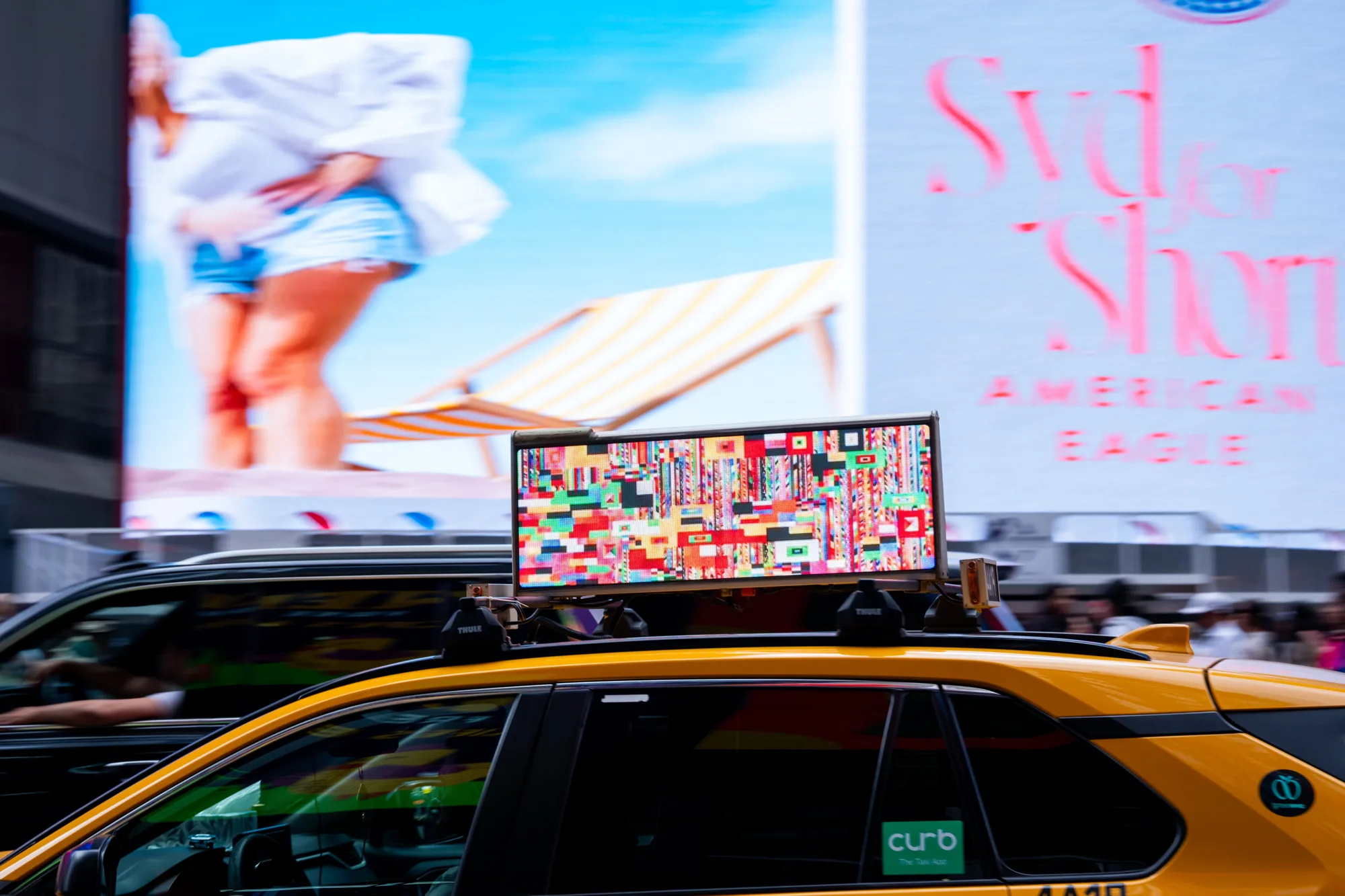 A taxi carrying the work through Times Square traffic
